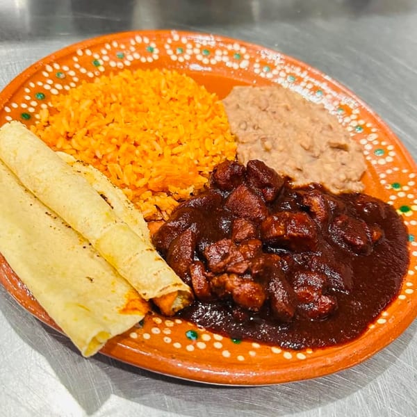 Taqueria Monterrey's mole poblano with rice, refried beans, and tortillas on a decorative orange plate.