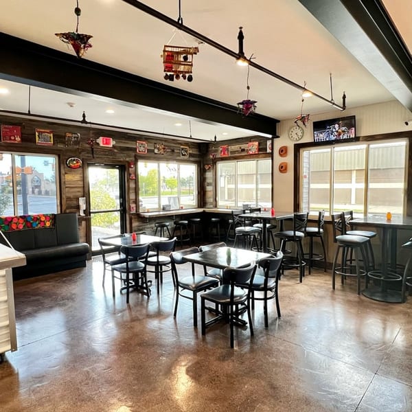 Interior of Taqueria Monterrey with tables, chairs, and bar seating along rustic wood-paneled walls.